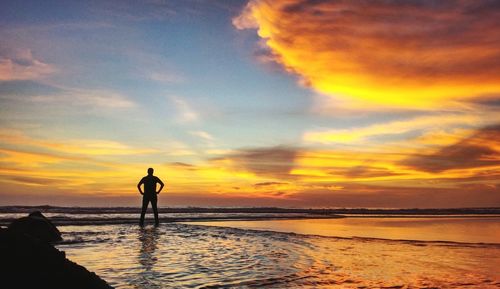 Silhouette man standing at beach against sky during sunset