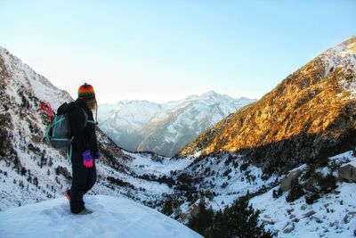 Rear view of man standing on snowcapped mountain