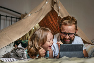 Father and son playing in a teepee tent at home.