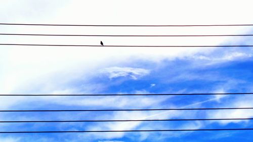 Low angle view of power cables against cloudy sky