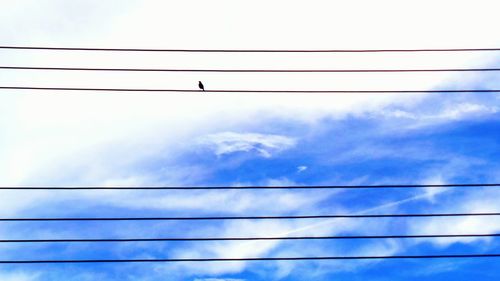 Low angle view of power cables against cloudy sky