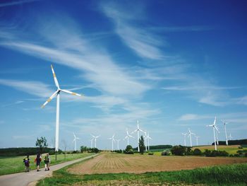 Windmills on field against sky