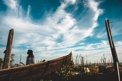 Woman sitting on boat against sky