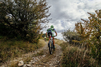 Man riding bicycle on plants against sky