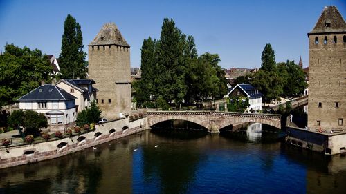 Bridge over river by buildings against sky