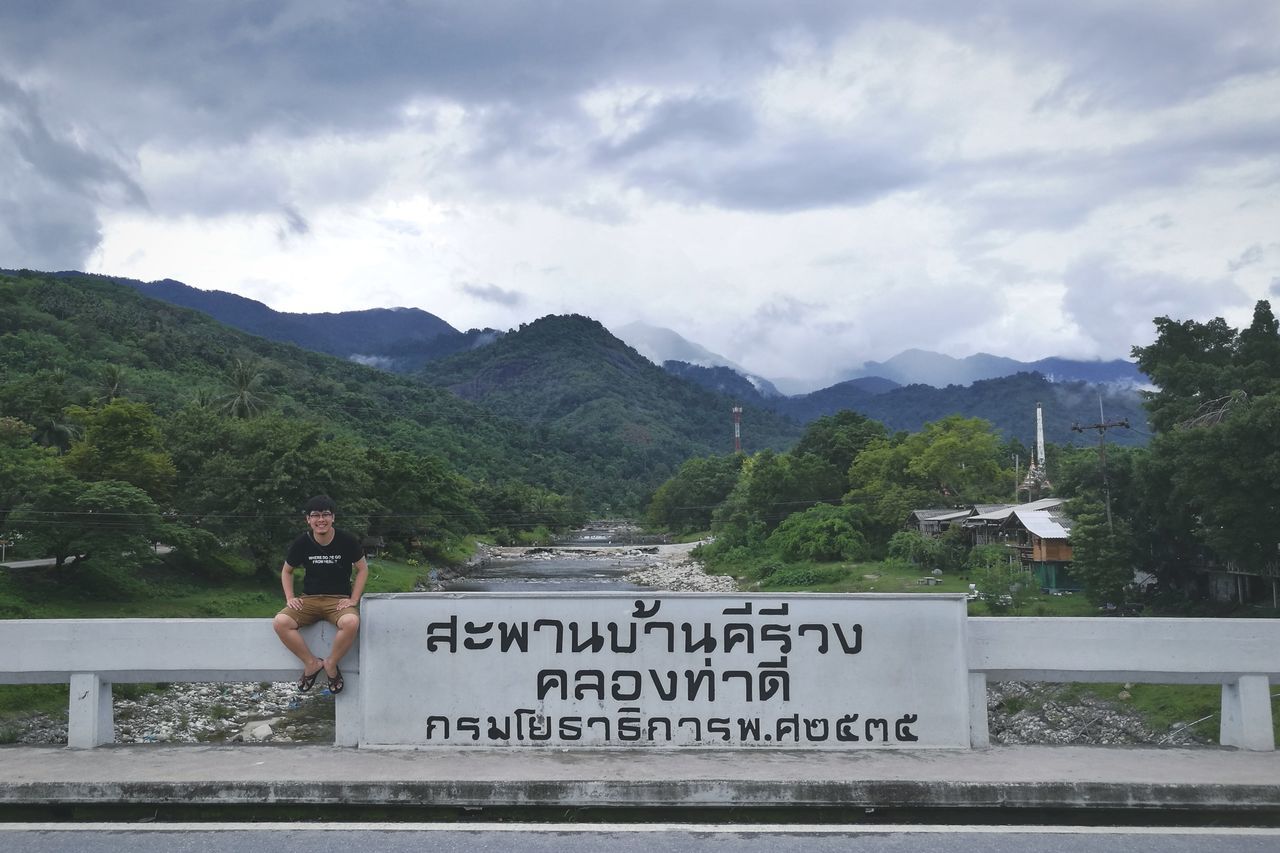 text, western script, communication, mountain, cloud - sky, sky, day, real people, outdoors, mountain range, one person, lifestyles, leisure activity, nature, beauty in nature, scenics, women, tree, men, architecture, people