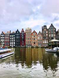 Buildings by canal against sky