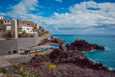 Scenic view of sea by buildings against sky