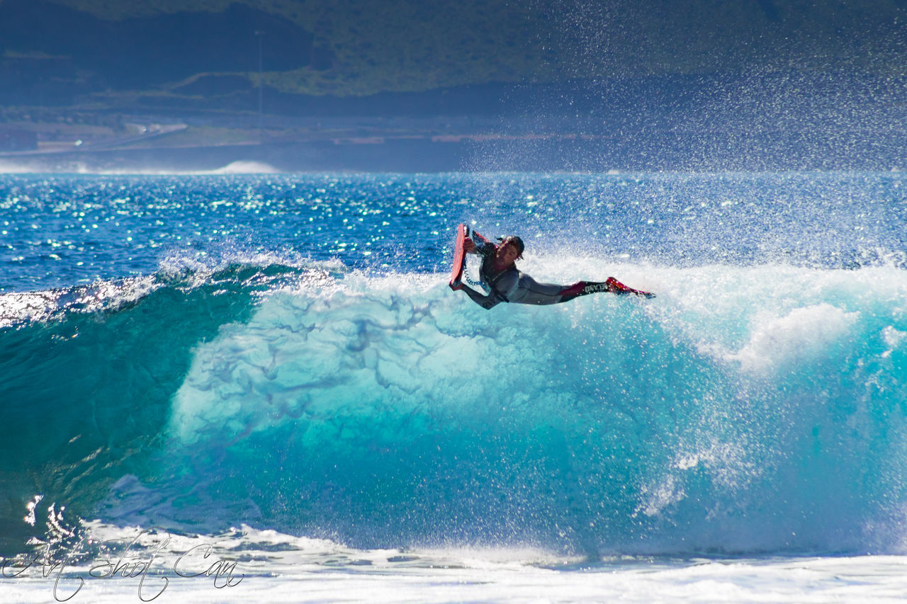 MAN SURFING ON SEA SHORE