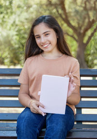 Young woman using laptop while sitting on bench at park