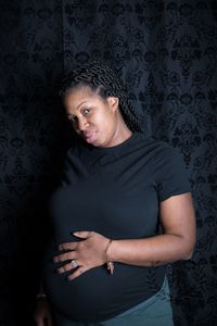 Portrait of pregnant woman standing against wall