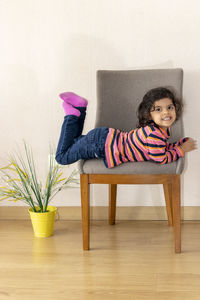 Portrait of cute girl lying on chair at home