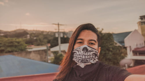 Close-up portrait of young woman against sky during sunset