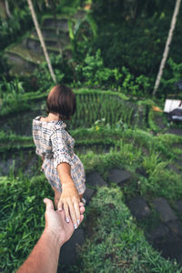 Midsection of woman with arms raised against plants