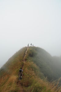 Friends hiking on mountain on foggy weather