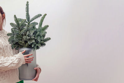 Unrecognizable woman holding a glass vase with decorative christmas tree branches