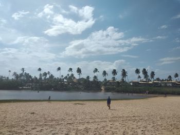 People playing on beach against sky