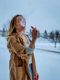 Midsection of woman standing by snow against sky