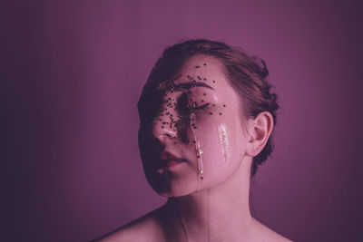 Close-up of woman with water and star shape decoration against pink background