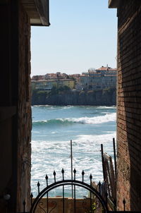 Scenic view of sea by buildings against clear sky