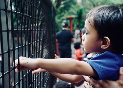 Close-up side view of girl holding cage