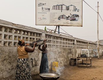 Man working at construction site in city against sky
