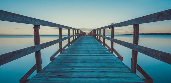 Footbridge over sea against clear sky