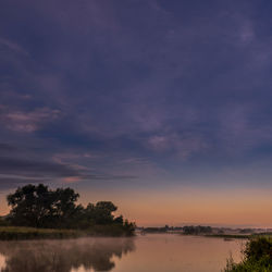 Scenic view of lake against sky at sunset