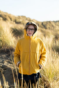 Tween standing in dunes covered in beach grass on the california coast