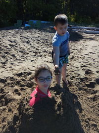 High angle view of siblings playing with sand at beach