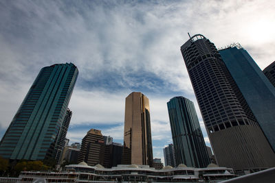 Low angle view of skyscrapers against cloudy sky