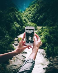 Cropped image of hand holding smart phone