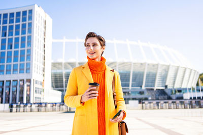 Portrait of young woman standing in city