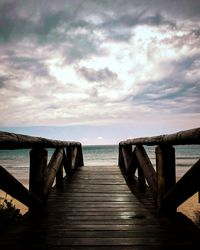 Wooden pier over sea against sky