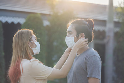 Young asia couple wearing face mask outdoors say hello with elbows outdoors. no hugs, no kisses,