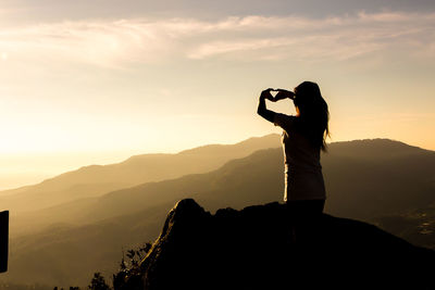 Silhouette woman on mountain against sky