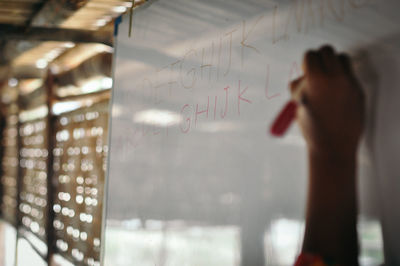 Midsection of woman standing by glass with text