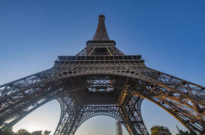 Eiffel tower seen from below with a blue sky in the background