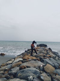 Full length of man on rock at beach against sky