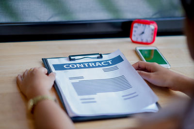 Midsection of person with contract paper at desk