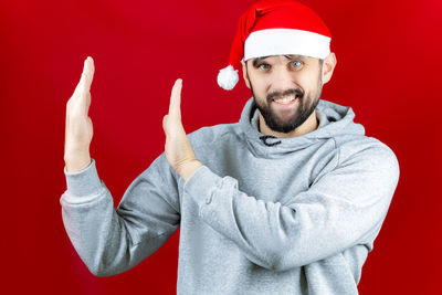 Portrait of smiling man wearing hat against red background