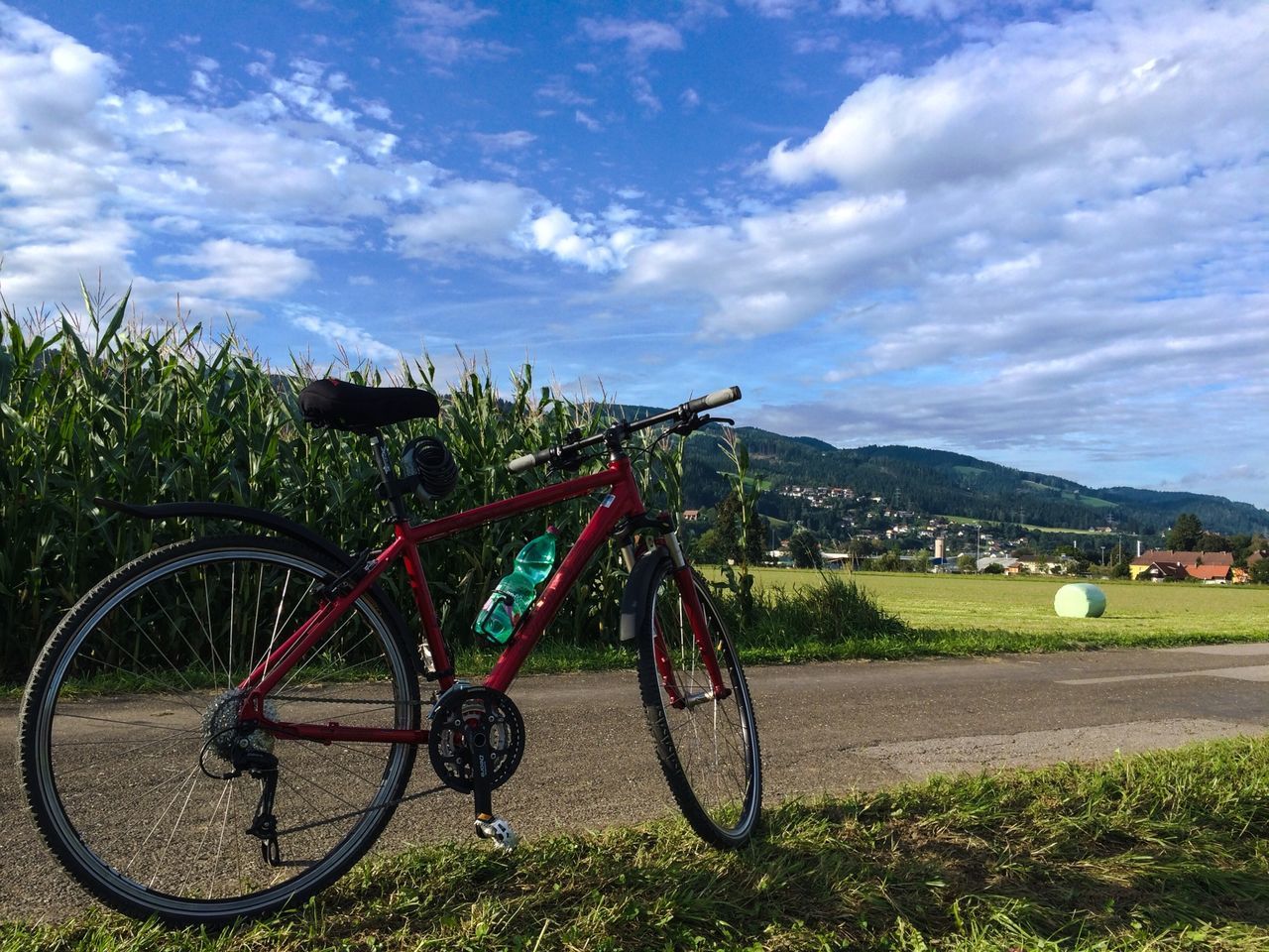 bicycle, transportation, land vehicle, sky, mode of transport, grass, cloud - sky, stationary, field, landscape, parking, parked, cloud, mountain, grassy, cloudy, tranquility, road, tranquil scene, day