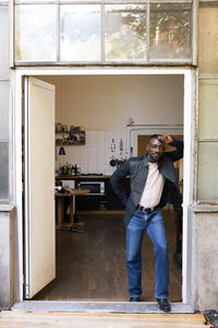 Side view of young man using mobile phone while standing against wall