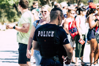 Rear view of men looking at people in city