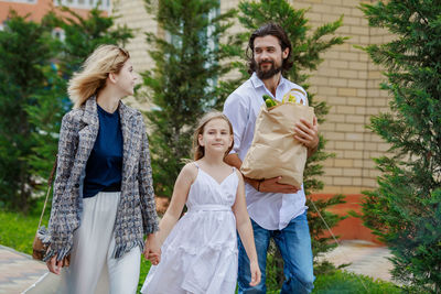 Parents with daughter walking against trees