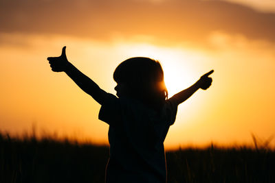 Silhouette woman with arms raised against sky during sunset