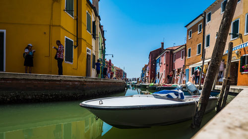 Boats moored on canal by buildings in city