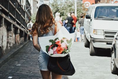 Woman holding umbrella while standing on street