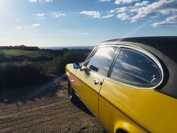 Car on road amidst field against sky