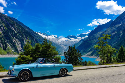 Car on road by mountains against blue sky